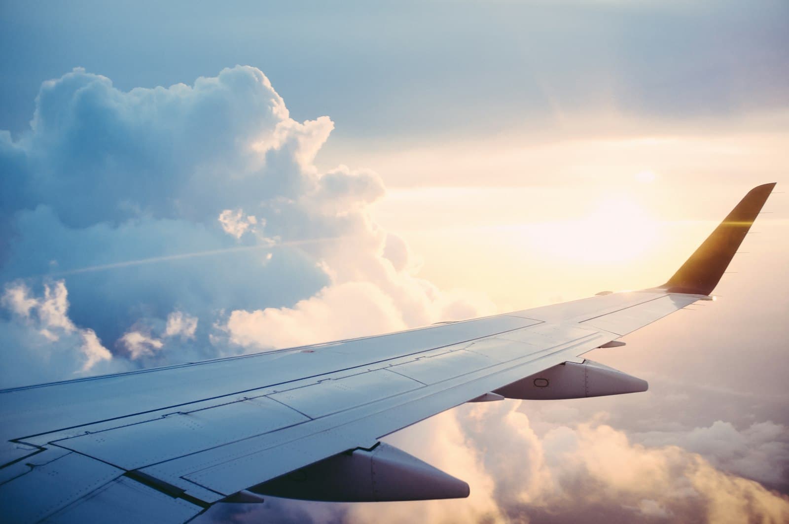 Airplane flying above clouds at sunset