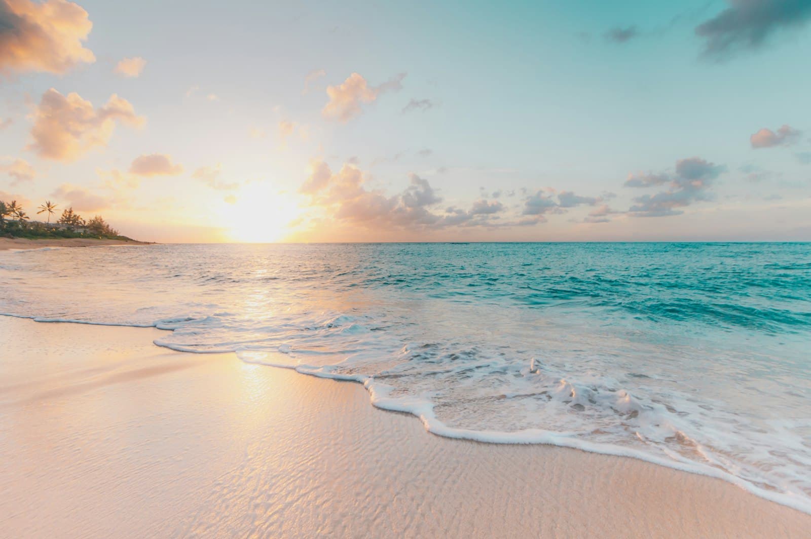 Pink sunrise over gentle surf on an empty beach